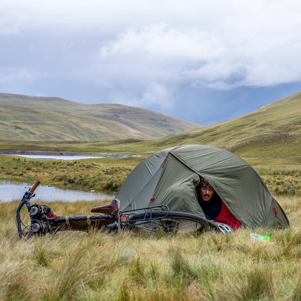 Thomas sous sa tente avec son vélo au Pérou, dans l'herbe