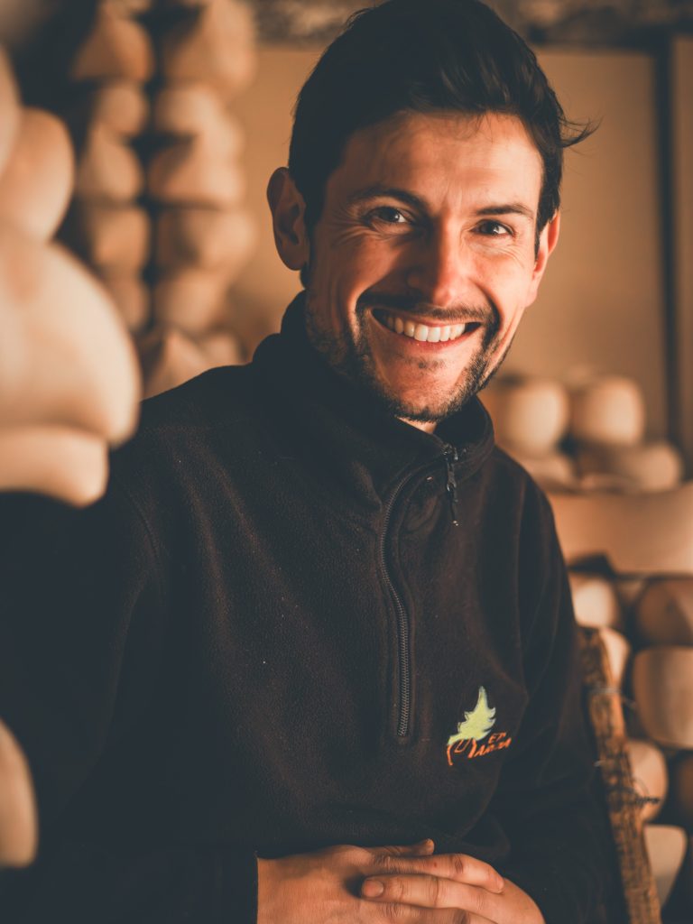 Pierre contre les sabots empilés dans l'atelier